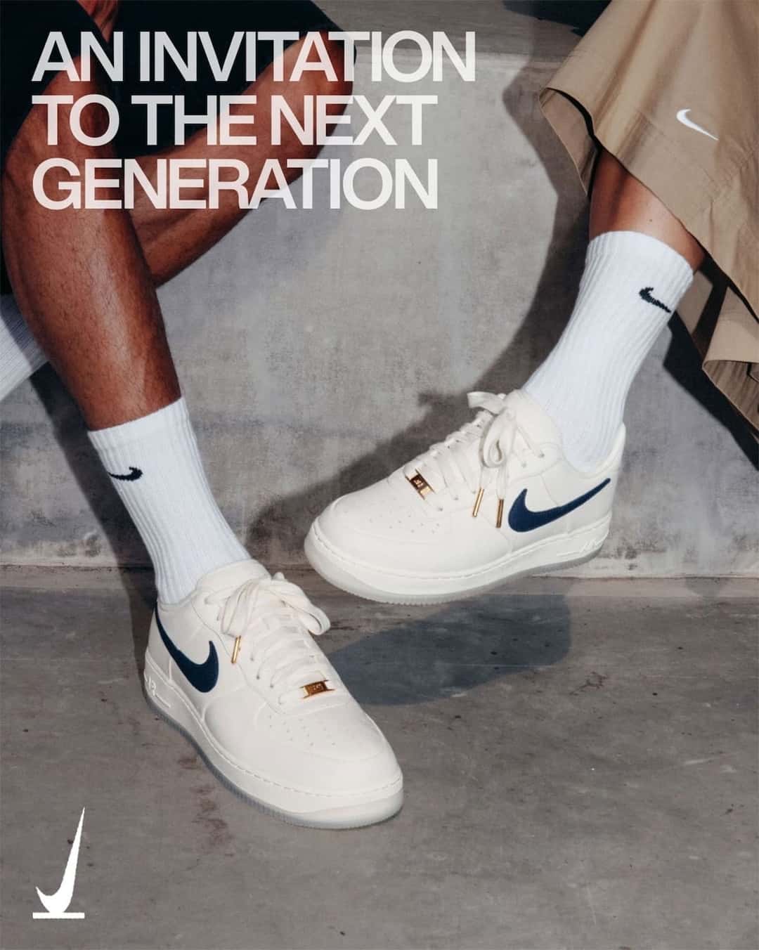 Dos personas sentadas sobre una pared de cemento con el Nike Air Force 1 SNKRS Friends & Family puesto, en cuero crema con Swoosh azul marino, puntas de cordones doradas y placa dorada en los cordones, en la imagen oficial de SNKRS con la frase An Invitation to the Next Generation