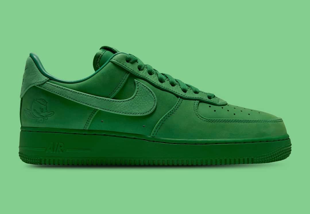 Nike Air Force 1 Low Luxe de la Universidad de Oregon de perfil lateral sobre fondo verde claro, entero en verde manzana, con el Swoosh de textura granulada y el pato de Oregon grabado en el talón
