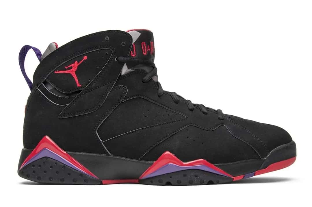 Foto de archivo: Air Jordan 7 Playoffs de la edición 2012 de perfil sobre fondo blanco, con upper de nubuck negro, Jumpman rojo, lengüeta con la inscripción Jordan en rojo y dientes rojos y violetas en la mediasuela