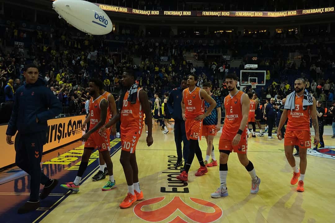 Foto de archivo: jugadores del Valencia Basket, con camisetas naranjas, caminan por la cancha de un estadio lleno después de un partido de Euroliga en enero de 2026