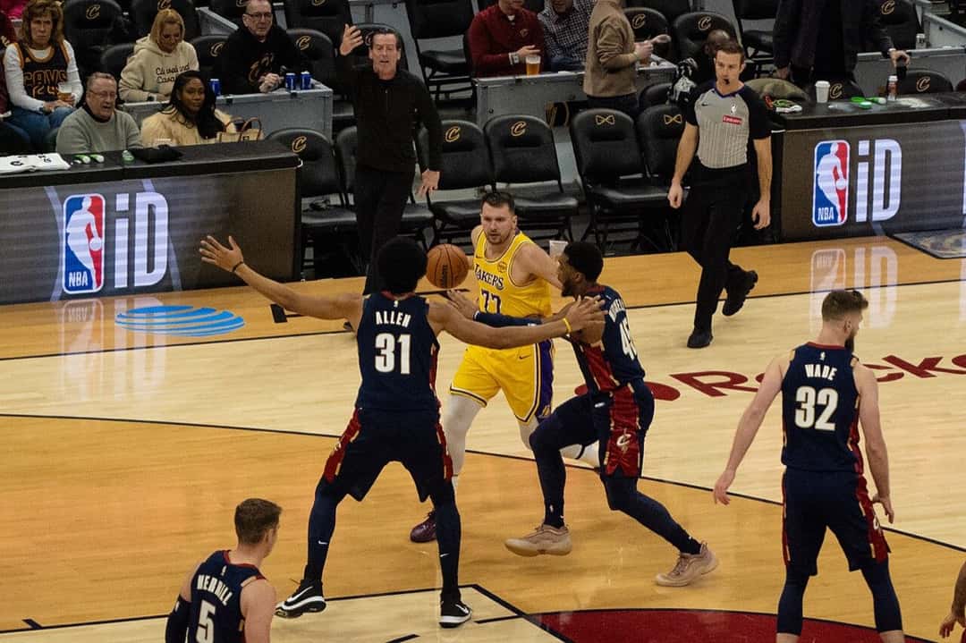 Luka Doncic, con la camiseta amarilla número 77 de los Lakers, recibe la marca de Jarrett Allen y Donovan Mitchell en un partido en Cleveland