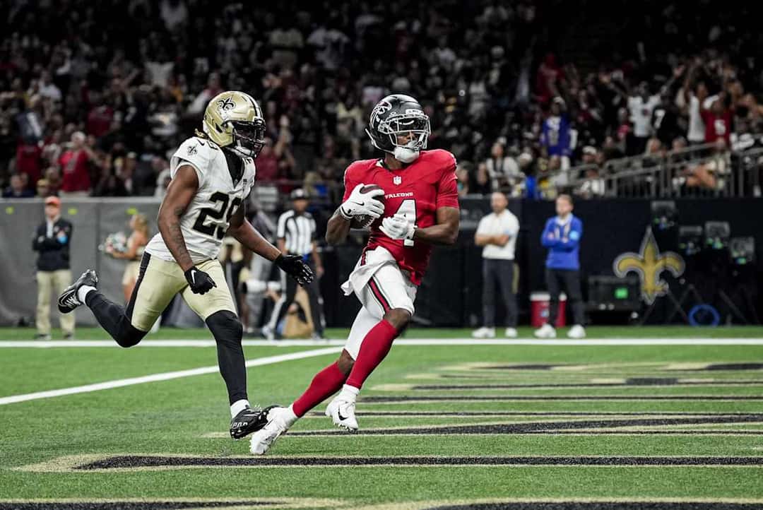 Jahan Dotson, con la camiseta roja número 4 de los Falcons, atrapa la pelota en la zona de anotación delante de un defensor de los Saints