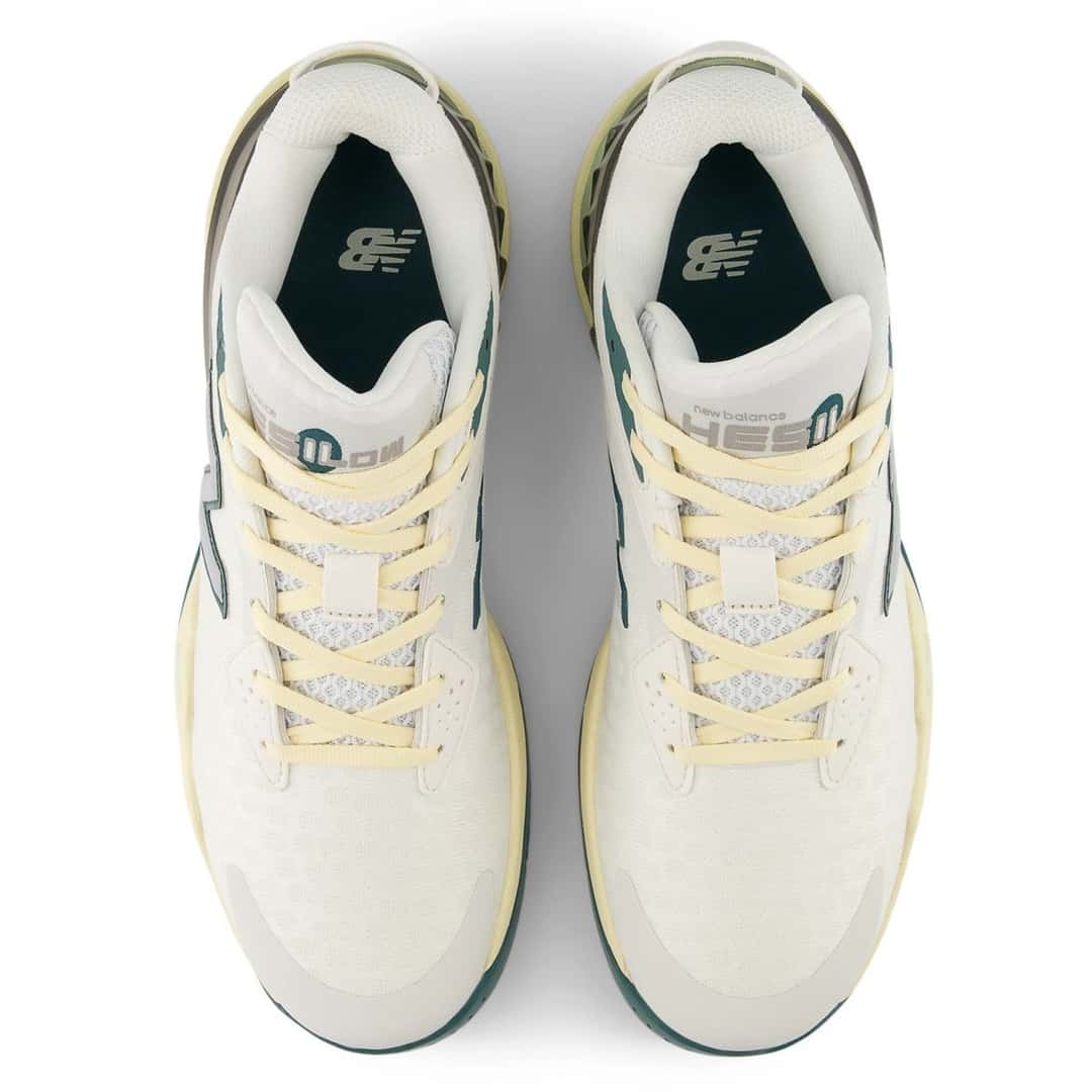 Par de New Balance Hesi Low v2 de Cooper Flagg visto desde arriba sobre fondo blanco, con cordones amarillo pálido, lengüeta con la inscripción new balance Hesi Low, plantillas verde petróleo con el logo NB y detalles verdes en los laterales; foto de archivo