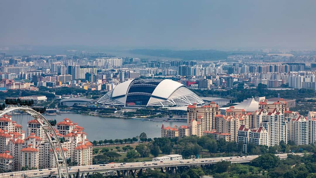 El Estadio Nacional de Singapur, con su techo en forma de cúpula blanca, visto desde lo alto junto al río y los edificios de la ciudad; foto de archivo de noviembre de 2019 (foto: Dietmar Rabich, Wikimedia Commons, licencia CC BY-SA 4.0)