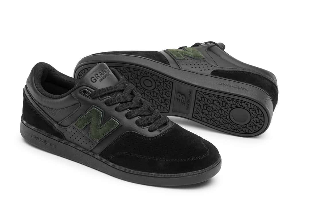 Par de New Balance Numeric 508 de Grand Collection en negro total de cuero y gamuza perforada, con la N en gamuza verde bosque, la palabra GRAND grabada en la lengüeta y una de las zapatillas dada vuelta mostrando la suela negra
