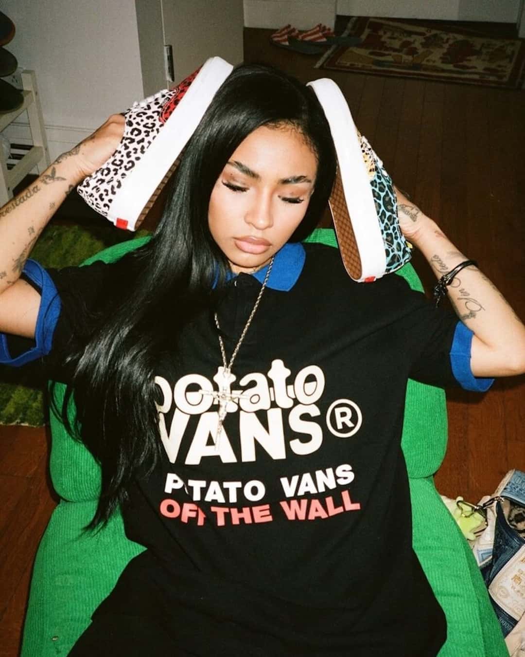 Modelo con remera negra con la leyenda Potato Vans sosteniendo los dos pies del Authentic desparejado, uno con cheetah rojo y blanco y otro con leopardo celeste