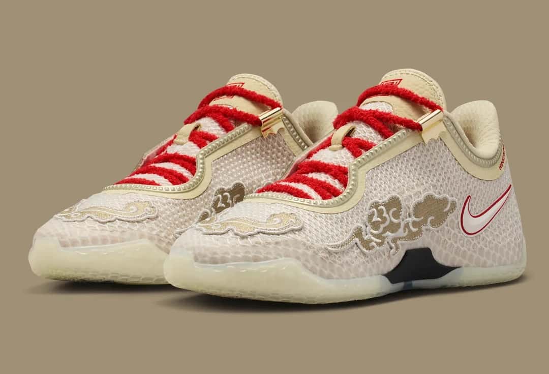 Par de Nike LeBron 24 Greater China en vista de tres cuartos sobre fondo caqui, con cordones rojos afelpados, nubes bordadas en dorado sobre la puntera y los laterales y suela translúcida