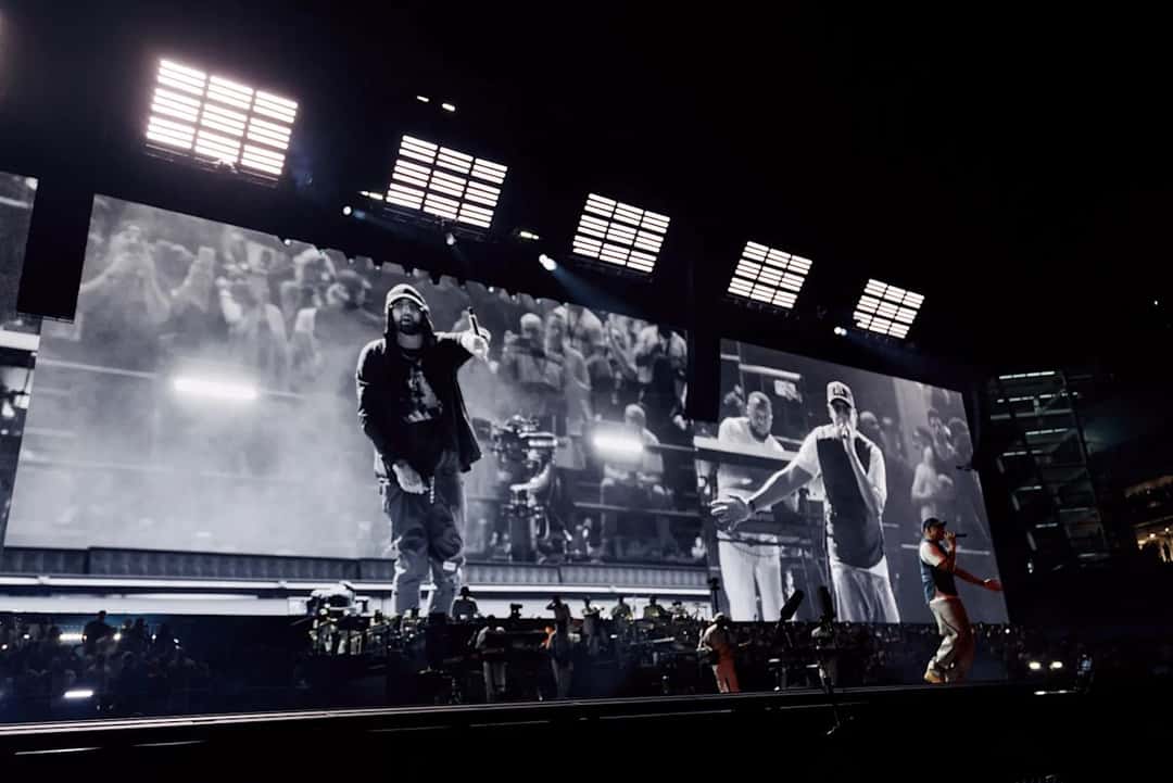 Foto oficial de la segunda noche en el Yankee Stadium: Jay-Z, con gorra y musculosa, rapea en el costado derecho del escenario mientras en las pantallas gigantes aparecen, en blanco y negro, Eminem con capucha y el propio Jay-Z. Foto: Roc Nation