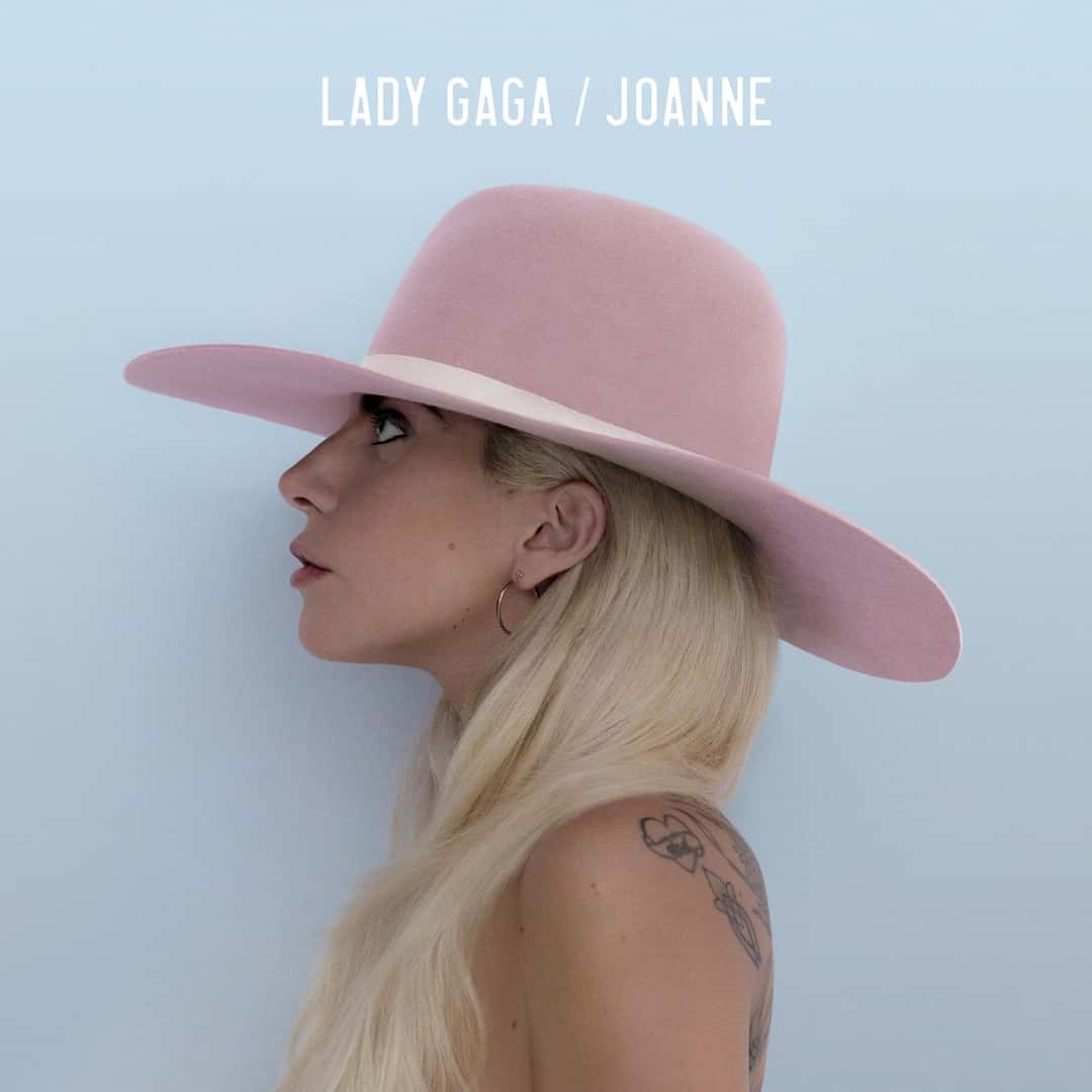 Portada de «Joanne», de Lady Gaga: la cantante de perfil, con un sombrero rosa de ala ancha y el pelo rubio suelto, sobre un fondo celeste
