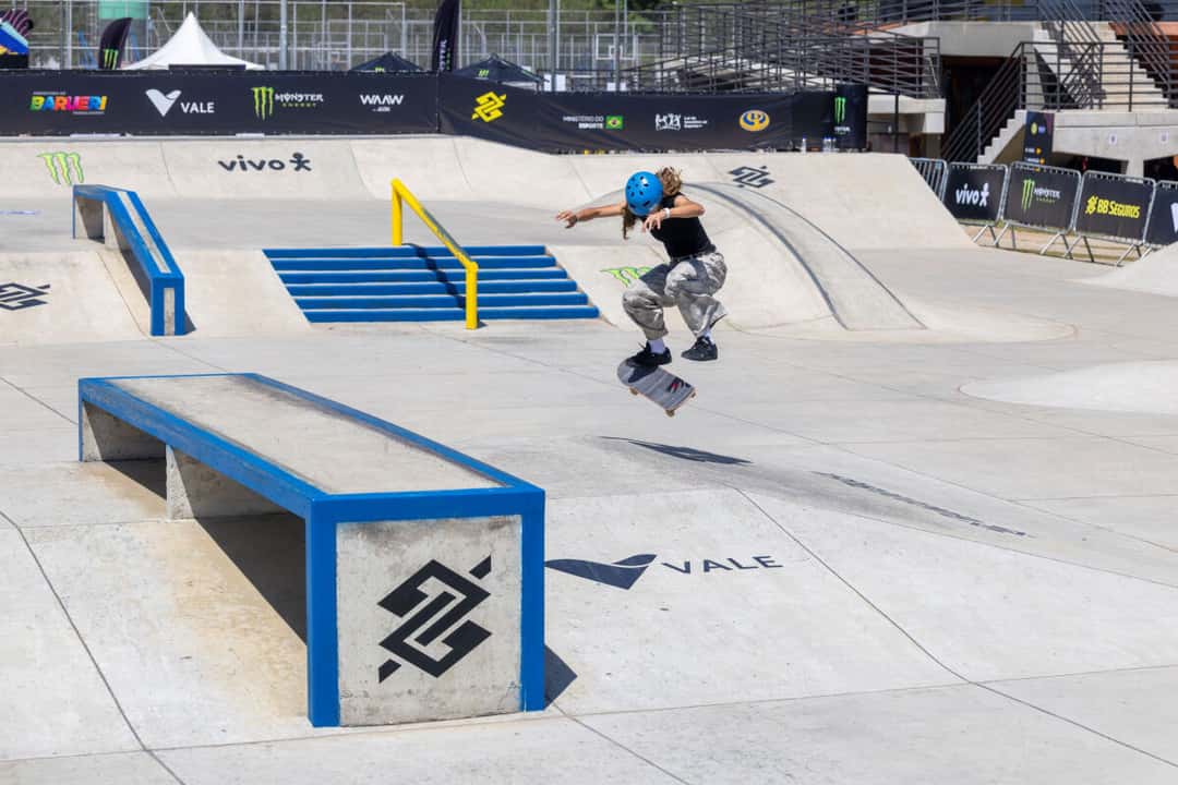 Una skater con casco azul salta con su tabla en la pista de street de Barueri, junto a un cajón azul con el logo del Banco do Brasil (foto de archivo)