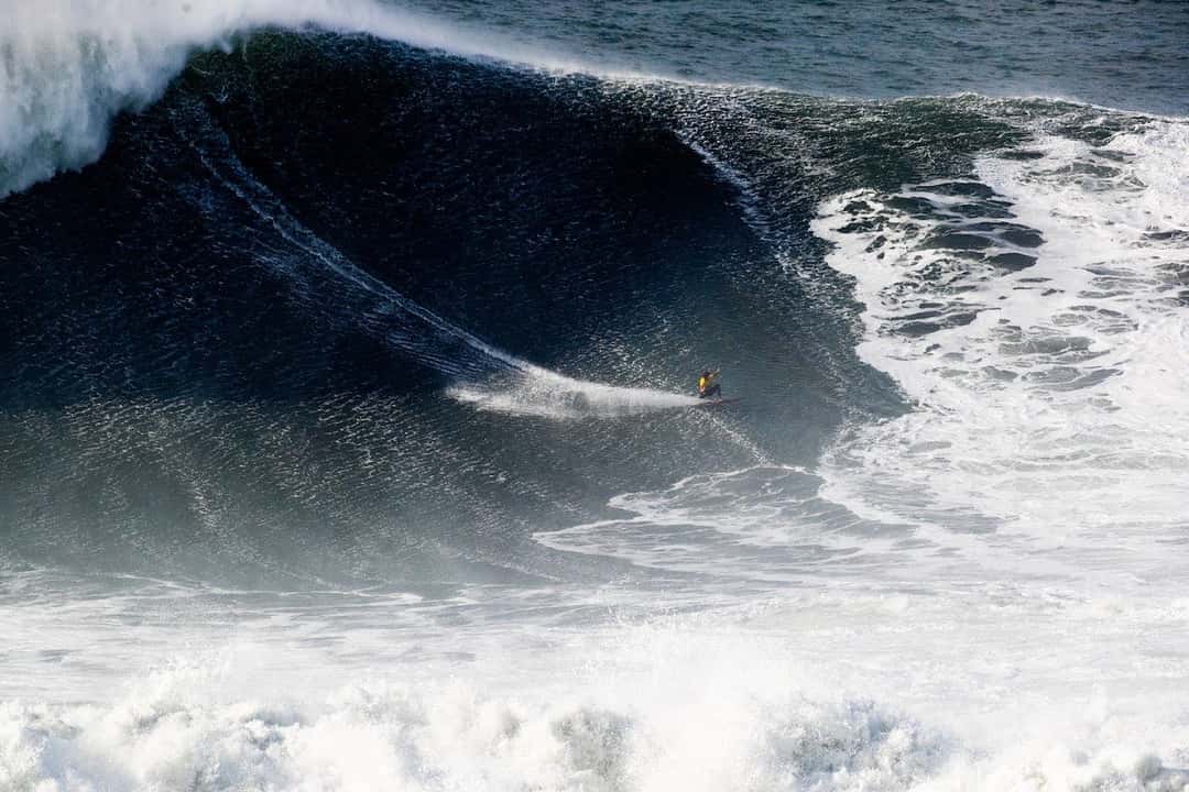 Foto de archivo: Justine Dupont, con traje amarillo, baja la pared de una ola enorme y oscura en Praia do Norte durante el Nazaré Big Wave Challenge del 13 de diciembre de 2025