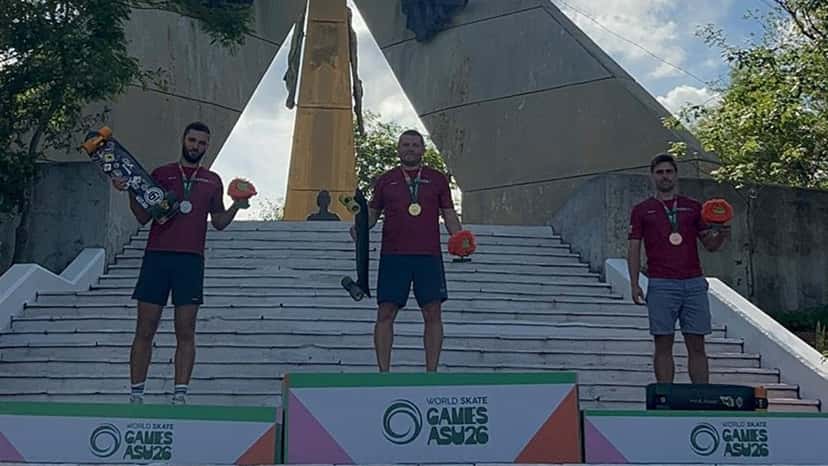 Tres skaters de Letonia, con camisetas bordó y medallas, en una escalinata de Asunción, sobre el podio de los World Skate Games