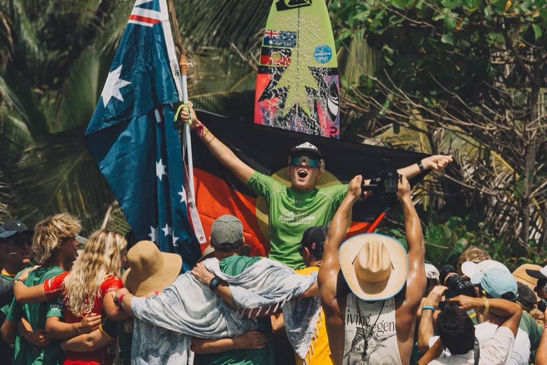 Leihani Zoric, con lycra verde y los brazos en alto, celebra sobre los hombros de sus compañeros con las banderas de Australia y aborigen detrás (foto de archivo)