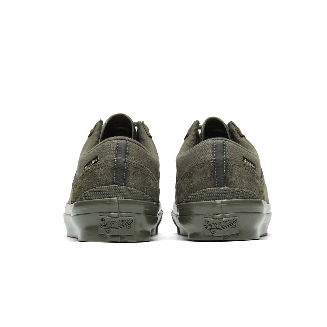 Talones del par Vans Premium Old Skool GORE-TEX Mossy Olive, con gamuza verde oliva, cinta gris oscura sobre la costura del talón, etiqueta GORE-TEX y el logo Off The Wall en la goma