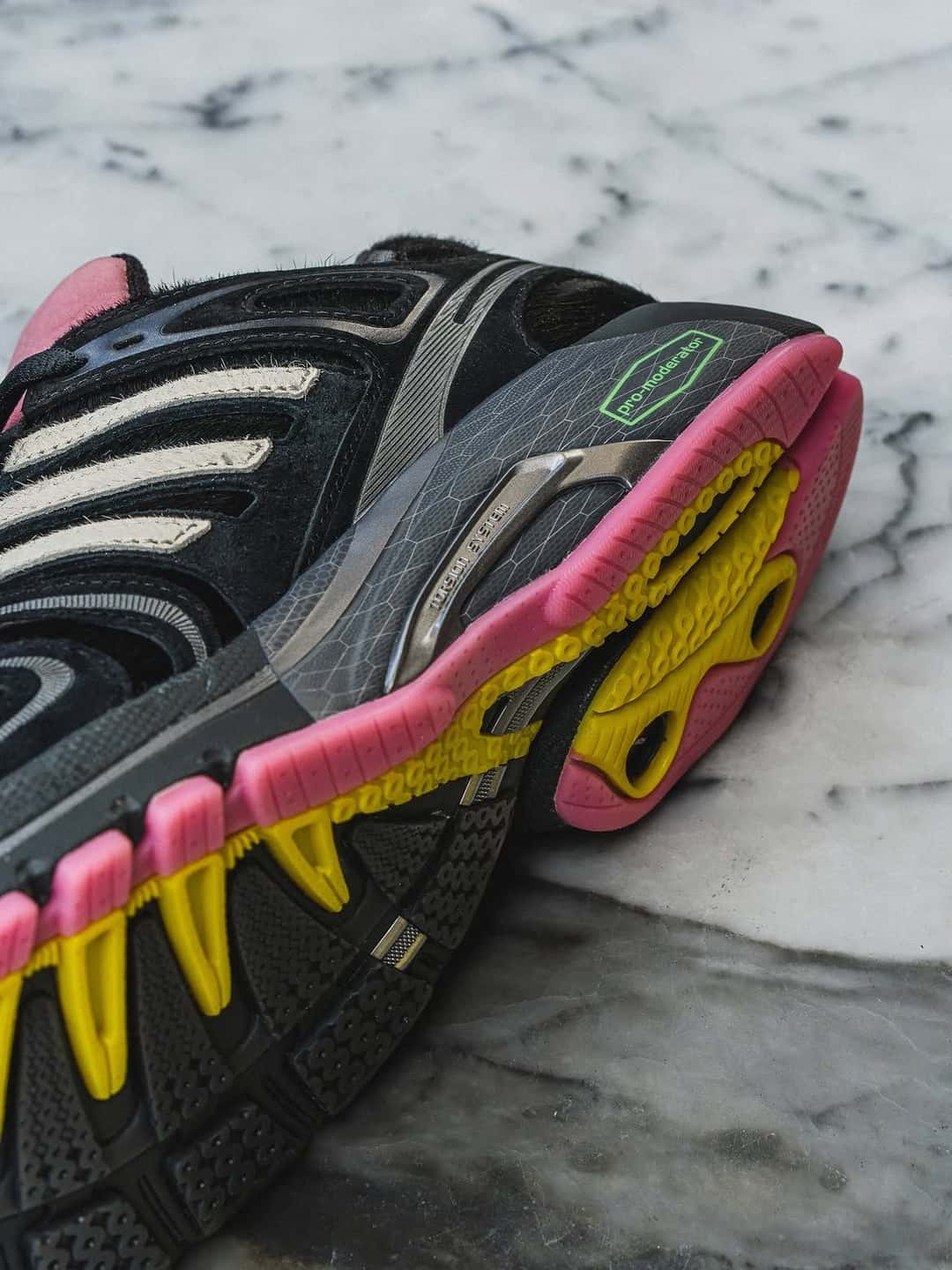 Suela de la adidas Adistar Control 5 Doggy Runner en rosa, amarillo y verde sobre una mesa de mármol