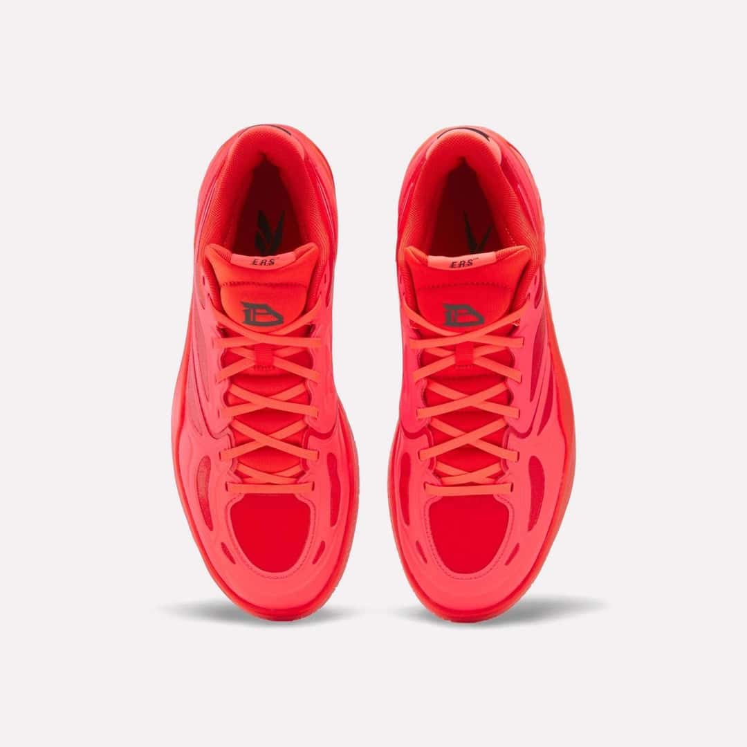 Par de Reebok Engine A de Darius Acuff Jr. visto desde arriba sobre fondo blanco, con los cordones rojos y el logo DA en las lengüetas
