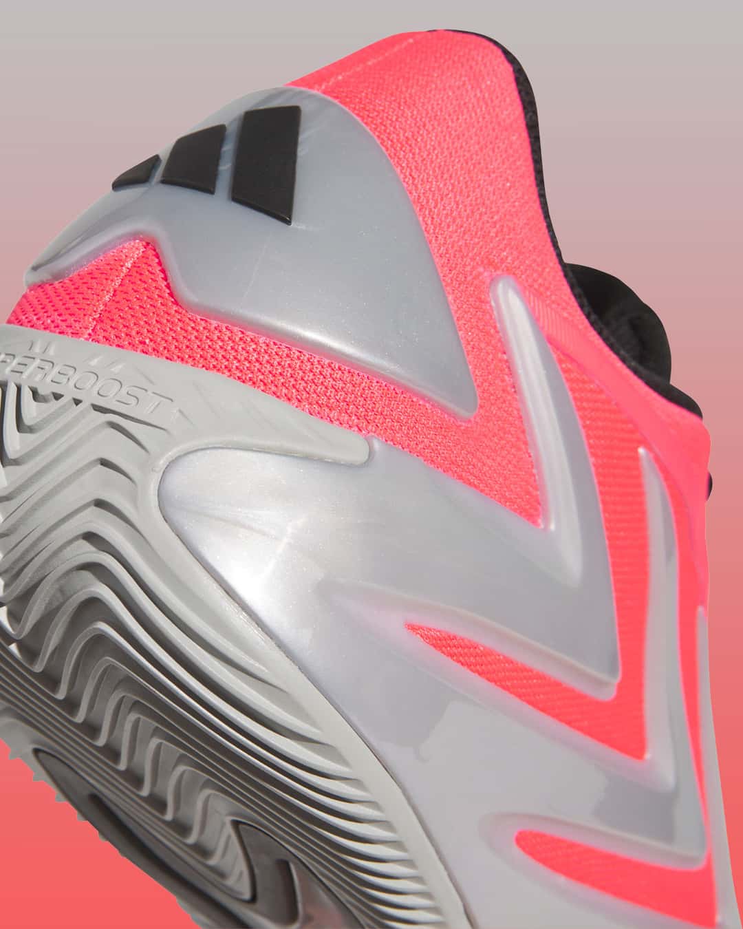 Primer plano del talón del adidas AE 3 Omen, con el clip plateado y las tres barras negras de adidas, la malla roja y la inscripción Hyperboost en la mediasuela gris