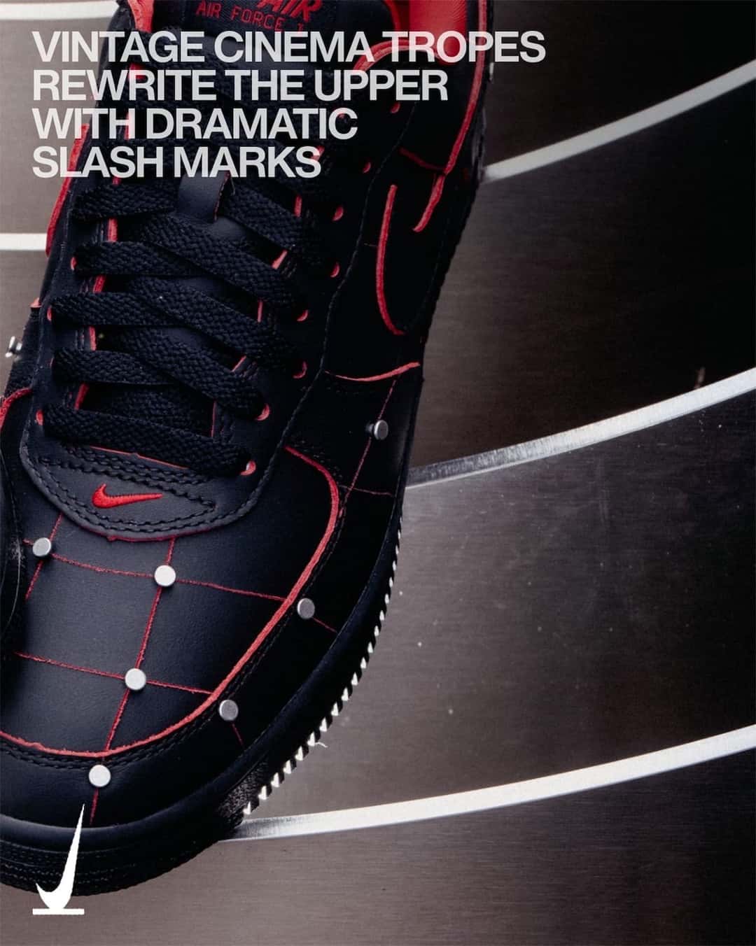 Vista lateral cercana del Nike Air Force 1 '01 Nightmare, con el cuero negro marcado por líneas rojas, tachas plateadas, el swoosh rojo en la puntera y el logo Air rojo en la lengüeta, con texto de campaña en inglés arriba