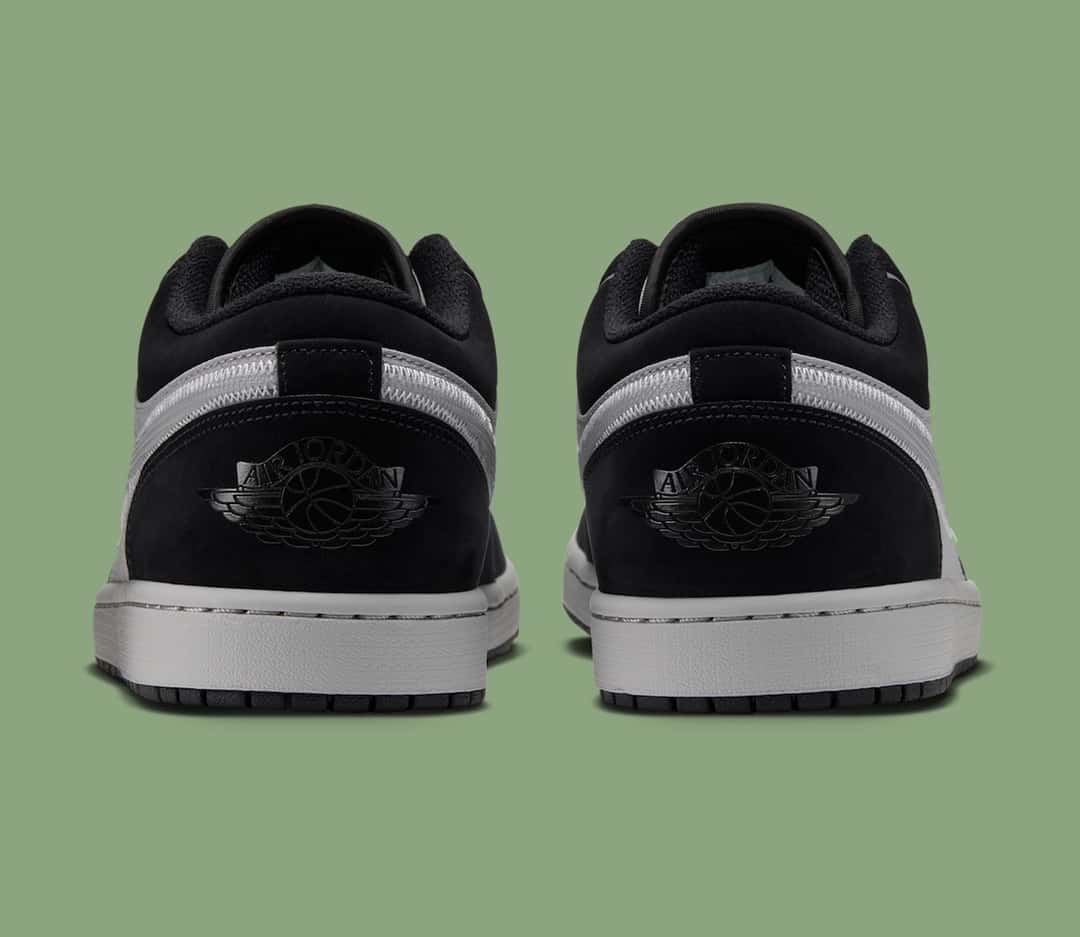Talones del Air Jordan 1 Low Light Smoke Grey Barely Volt sobre fondo verde, con el logo Wings negro sobre la gamuza negra, la mediasuela gris y la suela negra