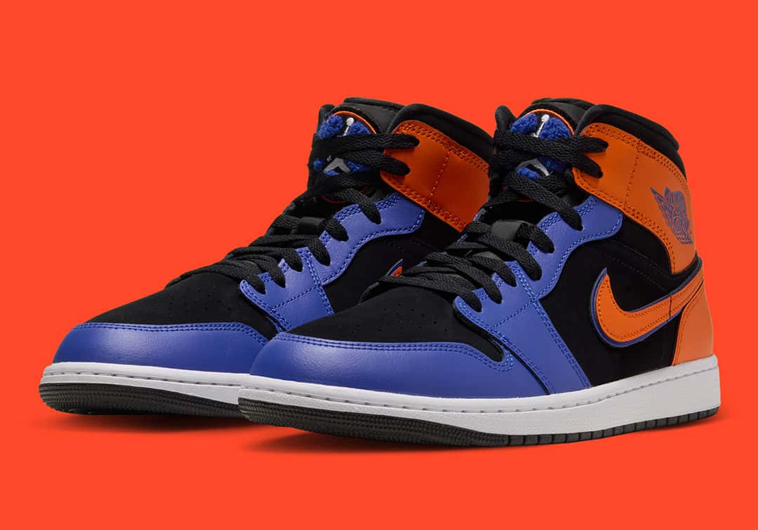 Par de Air Jordan 1 Mid Knicks de tres cuartos sobre fondo naranja, con el nobuk negro, el naranja y el azul real