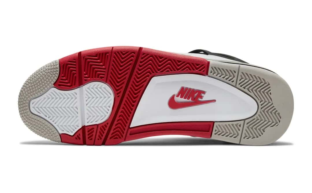 Foto de archivo: suela del Air Jordan 4 Fire Red de 2020 vista desde abajo, con sectores rojos y gris claro, una zona blanca con el logo Nike rojo en el centro y el patrón de espigas en la puntera y el talón