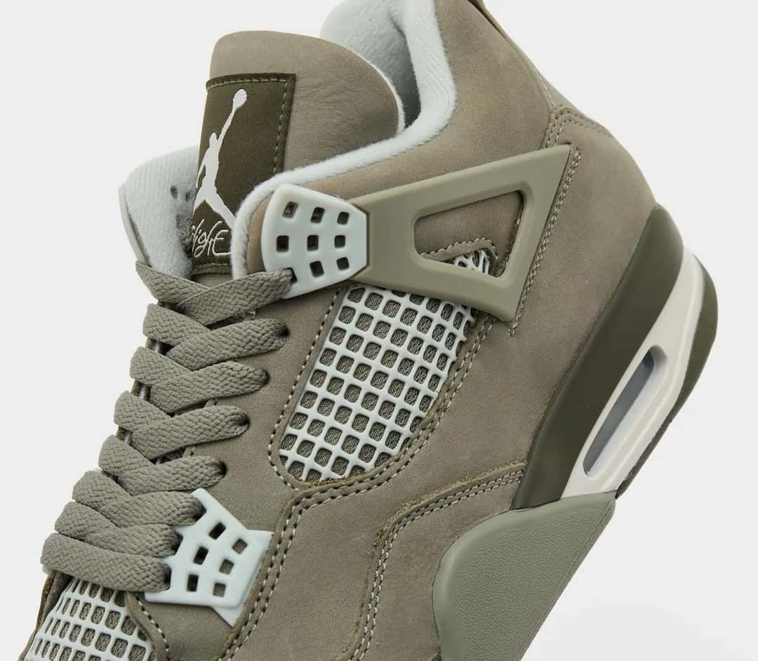 Primer plano del lateral del Air Jordan 4 Light Army, con los cordones verde oliva, el nubuck verde oliva, la malla y los ojales gris claro, el ala lateral del mismo tono que el upper, el parche oscuro de la lengüeta con el Jumpman blanco y la unidad Air visible en el talón