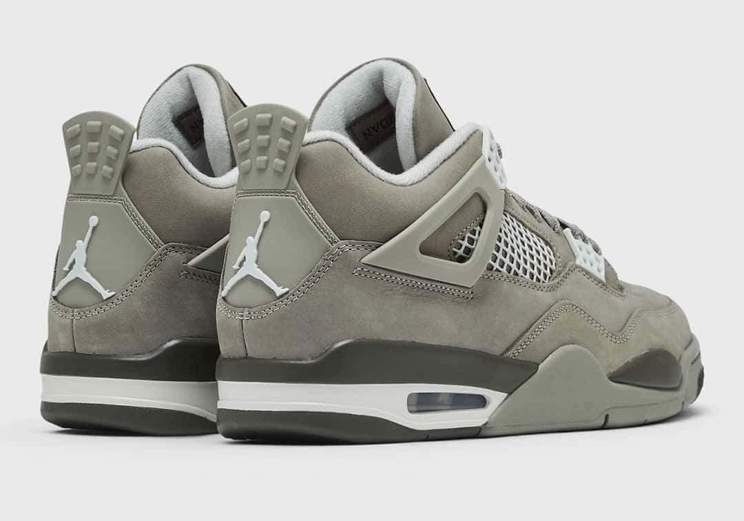 Vista trasera del par de Air Jordan 4 Light Army sobre fondo gris claro, con el Jumpman blanco en la pieza del talón, el forro gris claro, la mediasuela con una franja verde oliva oscuro sobre base blanca y la unidad Air visible en el lateral