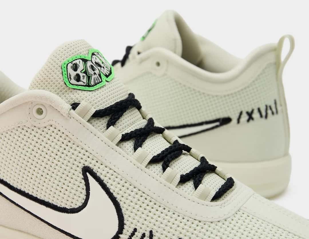 Detalle de la Nike Book 2 Oogie Boogie, con la lengüeta de logo verde y las costuras negras sobre el tejido color crudo
