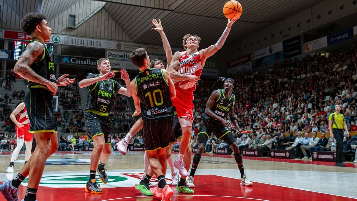 Nicolás Laprovittola, de espaldas con la camiseta negra número 10 del Joventut, marca a un jugador del Girona que lanza bajo el aro en el pabellón de Fontajau