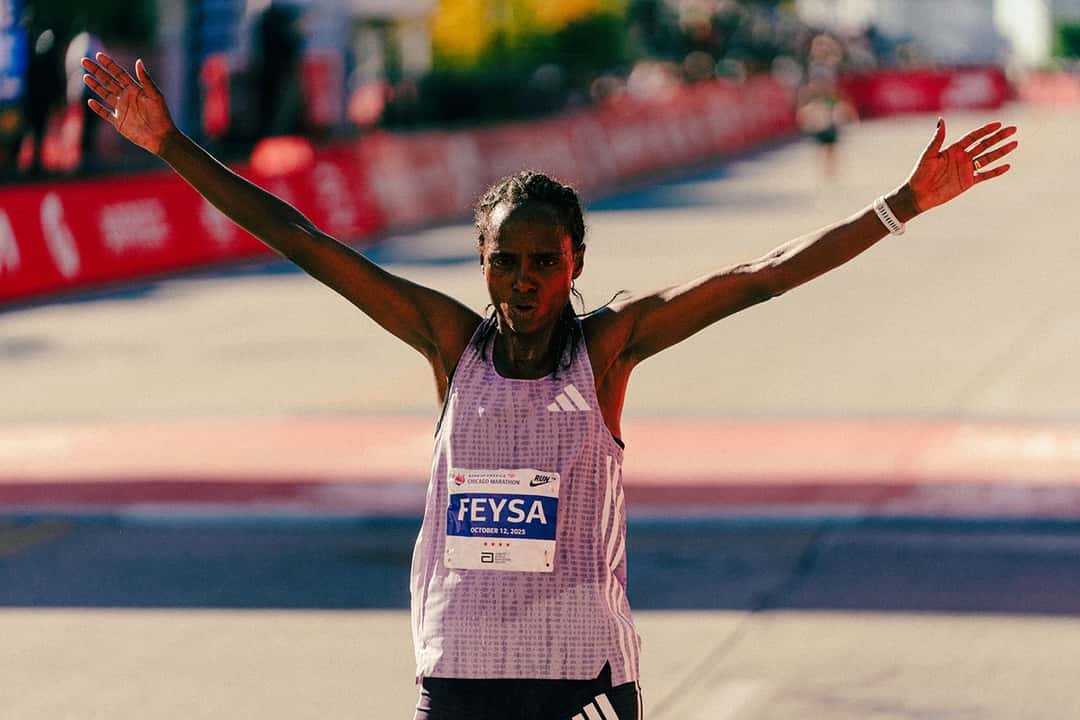 Foto de archivo: Hawi Feysa, con musculosa lila y el dorsal con su apellido, abre los brazos al llegar a la meta del Maratón de Chicago 2025