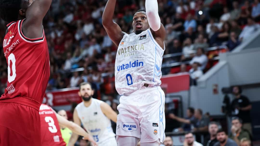 TJ Shorts, base del Valencia Basket con la camiseta blanca número 0, lanza en suspensión ante la marca de un jugador del Casademont Zaragoza en el Pabellón Príncipe Felipe