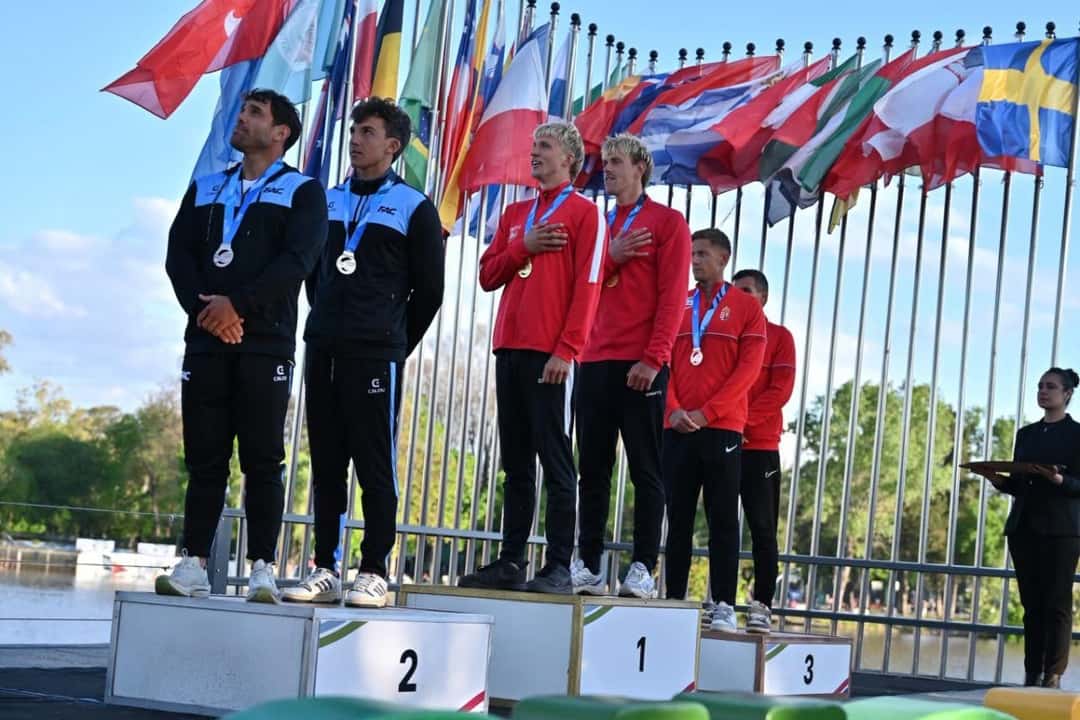 Los palistas argentinos, con campera negra, en el segundo escalón del podio, junto a los ganadores daneses y a los húngaros, con las banderas de los países detrás