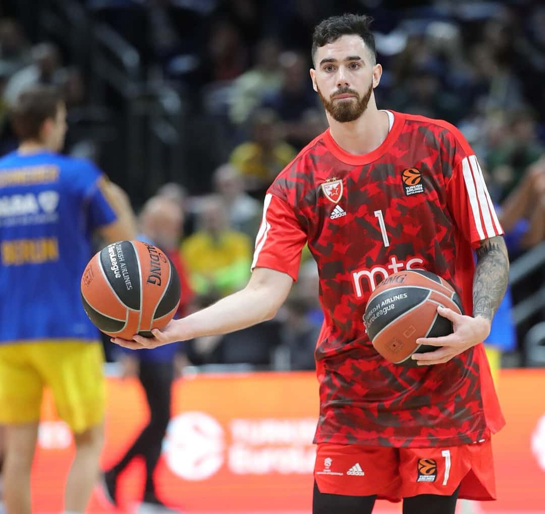 Foto de archivo: Luca Vildoza, con la remera roja de entrada en calor del Crvena zvezda y el número 1, sostiene dos pelotas de básquet antes de un partido de Euroliga