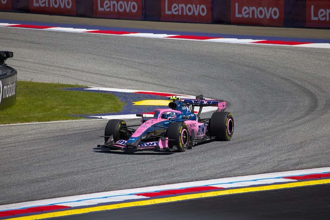 Foto de archivo: el Alpine azul y rosa número 43 de Franco Colapinto sale de una curva del Red Bull Ring, con los pianos rojos y blancos y la tribuna de fondo