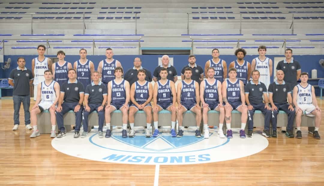 El plantel de Oberá posa sentado y de pie con la camiseta azul y blanca sobre el parquet, con el logo de Misiones en el círculo central