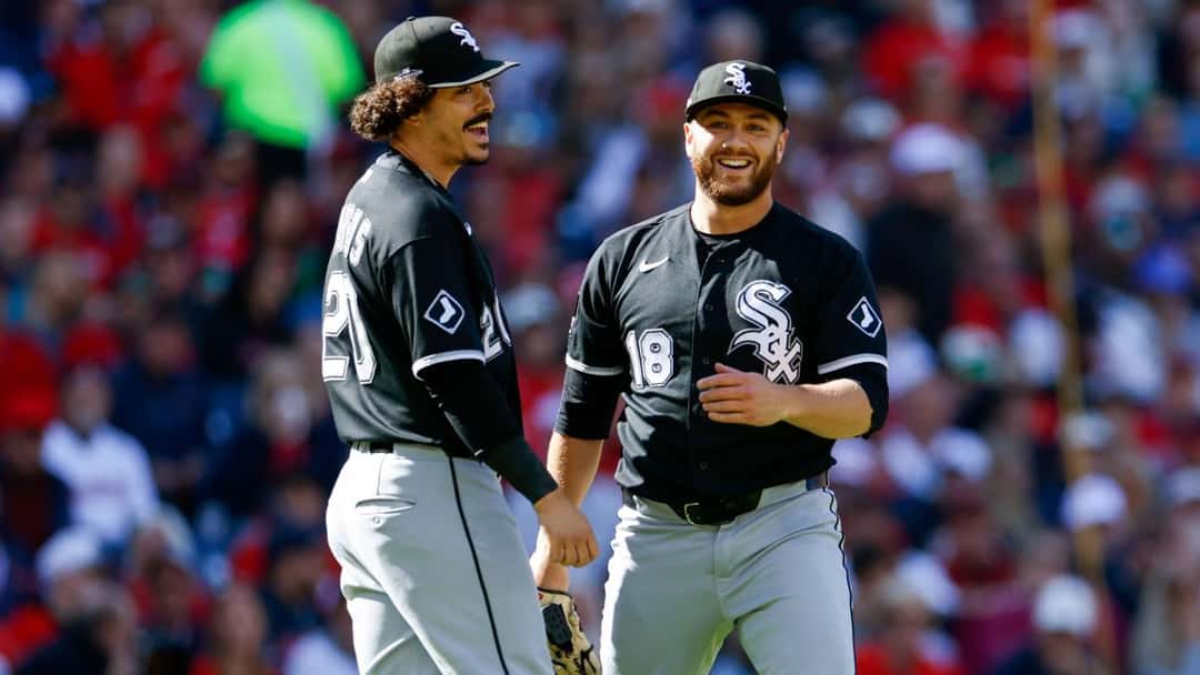 Dos jugadores de los White Sox sonríen en el campo de Progressive Field, con la tribuna de Cleveland de fondo