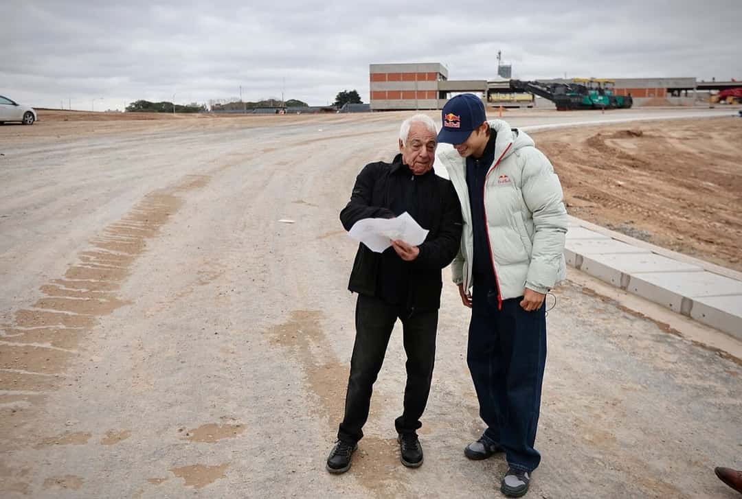 Foto de archivo: Valentín Perrone conversa con el ex piloto Chiche Caldarella, que lee unos papeles, sobre el asfalto en obra del autódromo de Buenos Aires