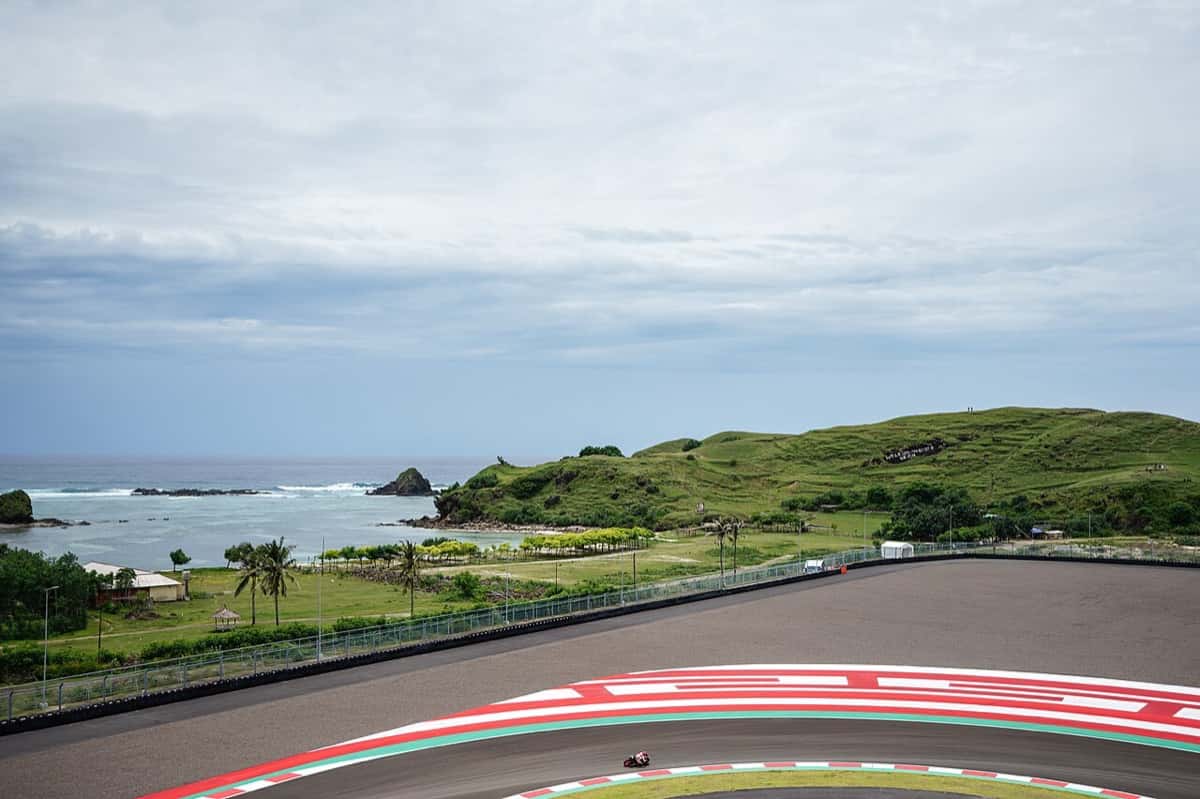 Foto de archivo: una moto de MotoGP pasa por la curva 10 del circuito de Mandalika, con el mar y una colina verde de fondo
