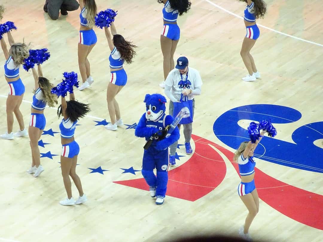 Foto de archivo: bailarinas del equipo de animación de los 76ers, con pompones azules, y la mascota del club en el centro de la cancha