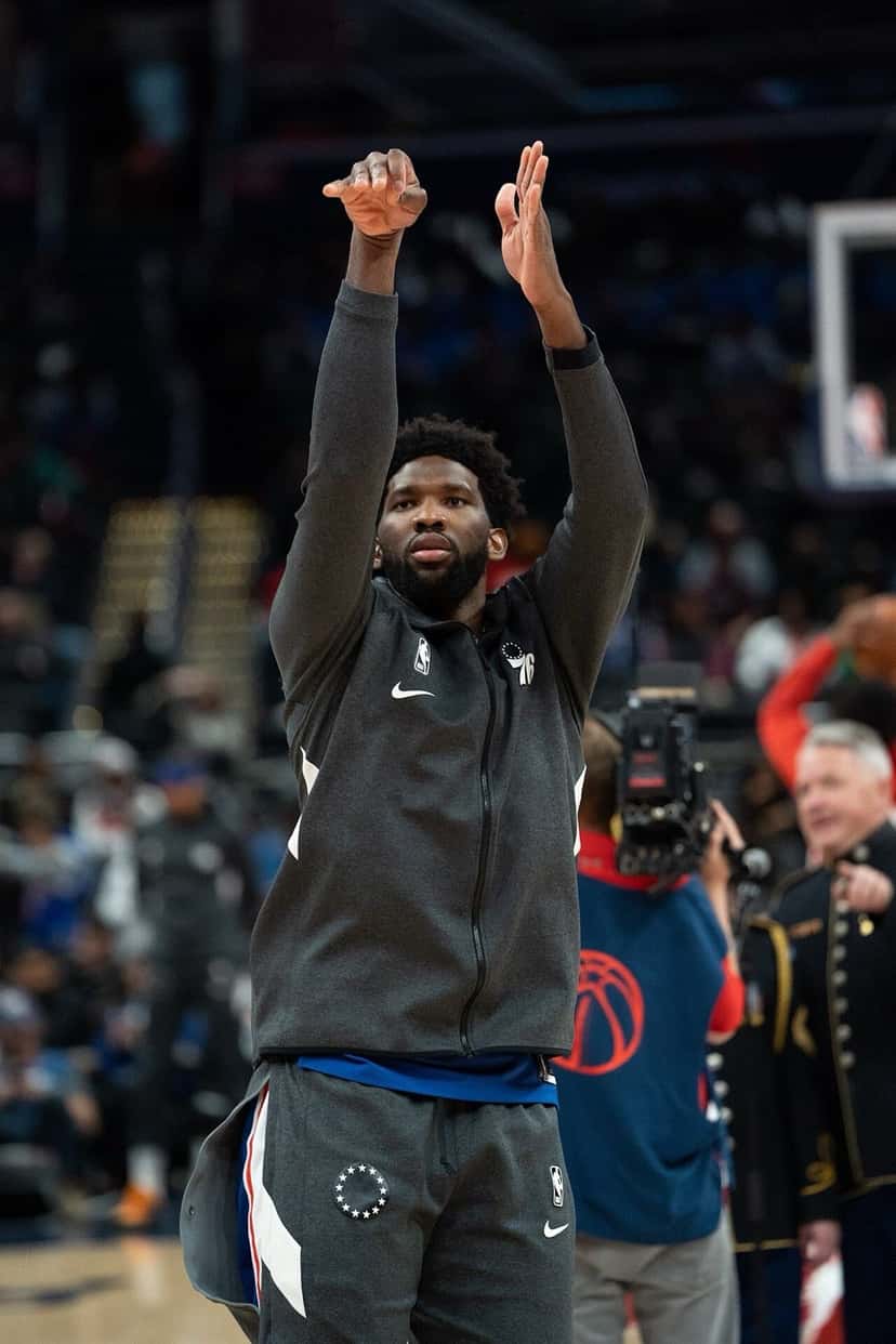Foto de archivo: Joel Embiid, con campera gris de los 76ers, lanza en la entrada en calor antes de un partido, con el público de fondo