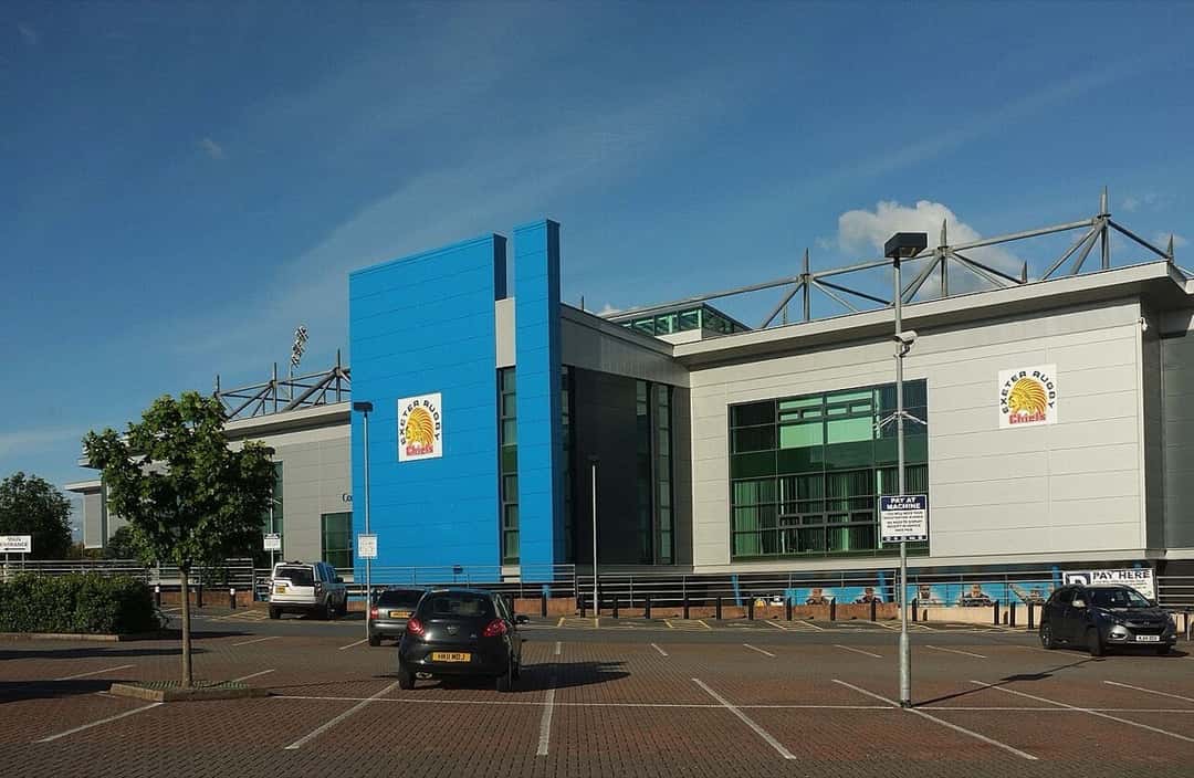 Foto de archivo: el estadio Sandy Park de Exeter visto desde el estacionamiento, con su fachada gris y azul y el escudo de los Chiefs, en un día de sol