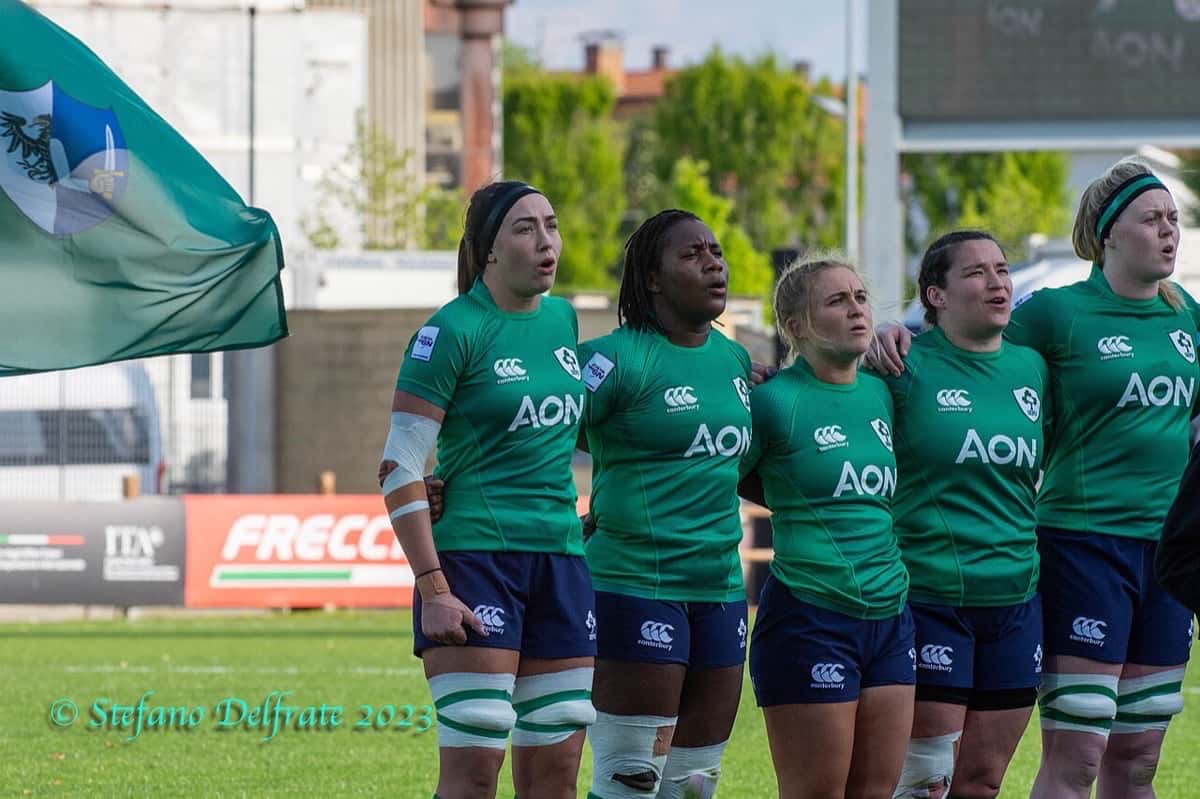Foto de archivo: cinco jugadoras de Irlanda, con la camiseta verde, cantan el himno abrazadas antes de un partido del Seis Naciones femenino 2023, con una bandera detrás