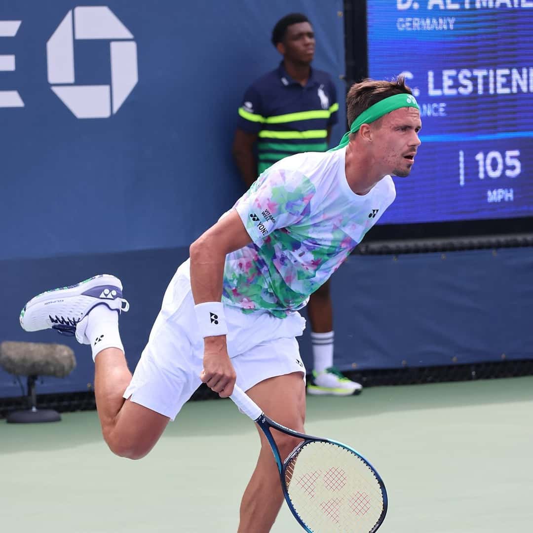 Foto de archivo: Daniel Altmaier, con remera floreada y vincha verde, termina el movimiento del saque en el US Open 2023