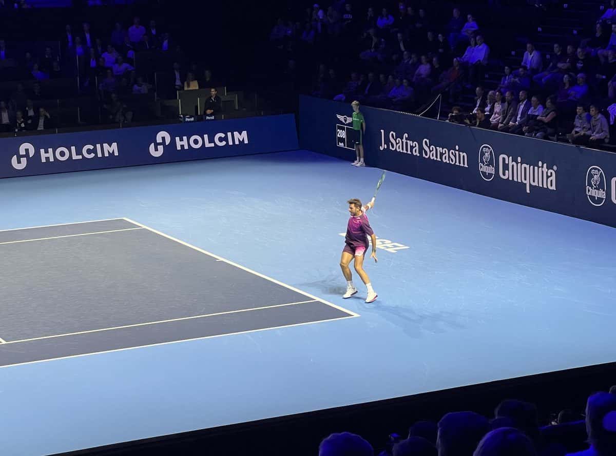 Foto de archivo: Stan Wawrinka, de remera violeta, termina un revés en la cancha azul de Basilea, con el estadio en penumbras