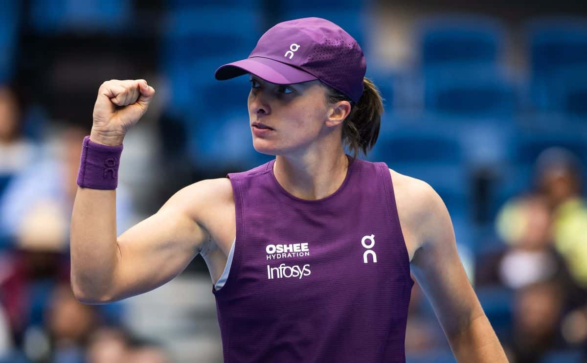 Iga Swiatek, con gorra y musculosa violeta, aprieta el puño durante un partido del China Open 2026