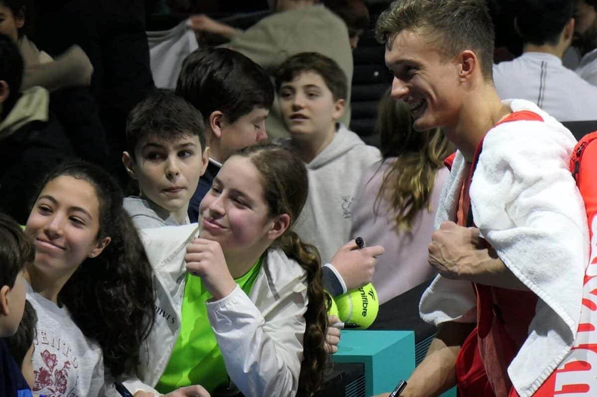 Foto de archivo: Jiri Lehecka, con una toalla blanca sobre los hombros, sonríe mientras firma autógrafos a chicos en la tribuna del torneo de Róterdam