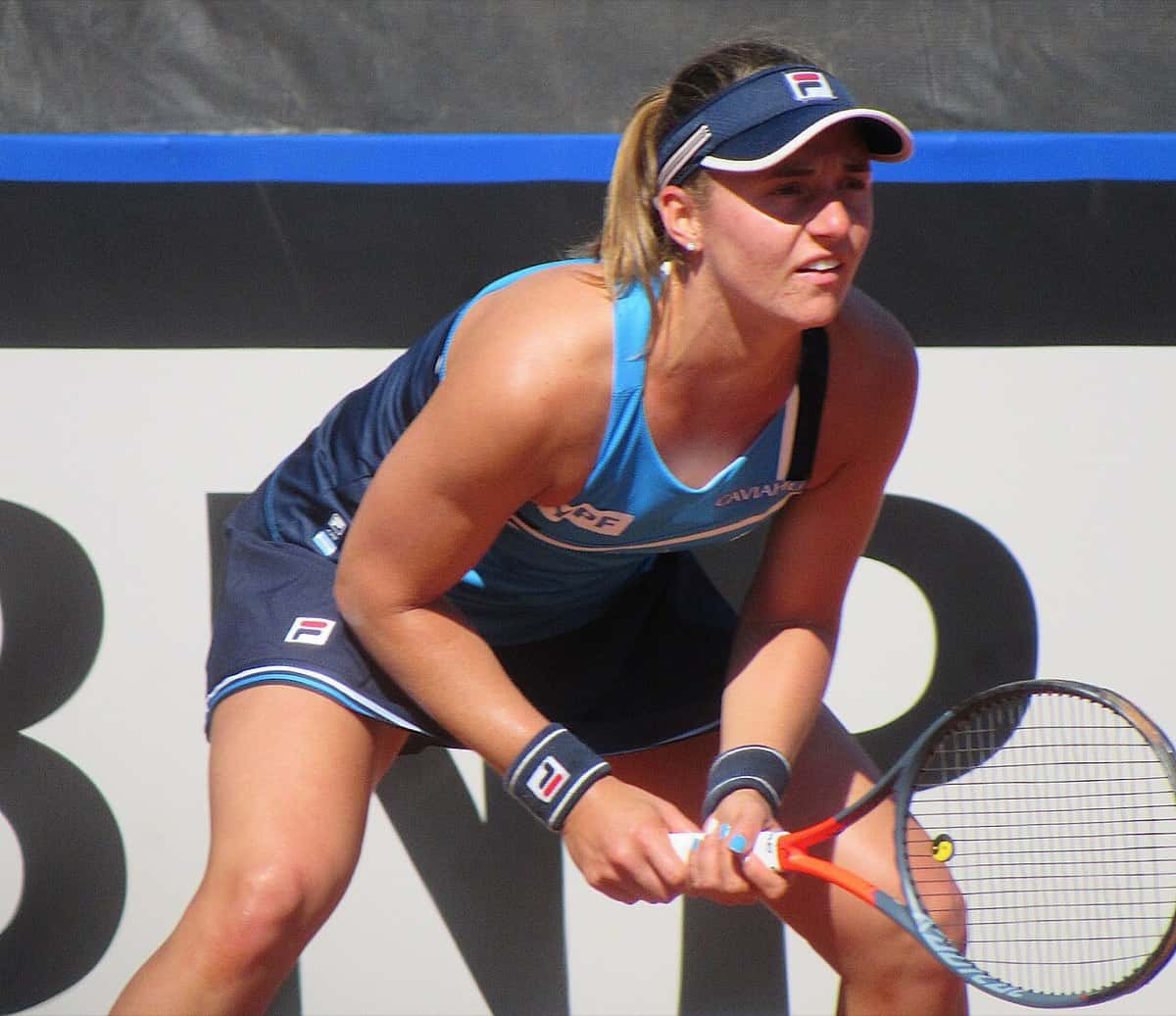 Foto de archivo: Nadia Podoroska, con visera y musculosa azul, espera la devolución con la raqueta en las dos manos en un partido de la Billie Jean King Cup en Córdoba