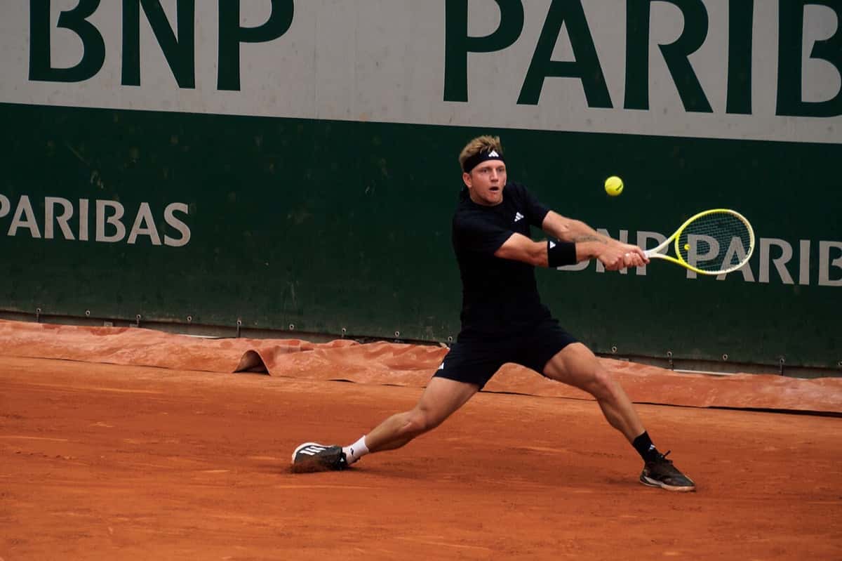 Foto de archivo: Alejandro Davidovich Fokina, con vincha y ropa negra, se estira para pegar un revés en una cancha de polvo de ladrillo, delante de un cartel verde