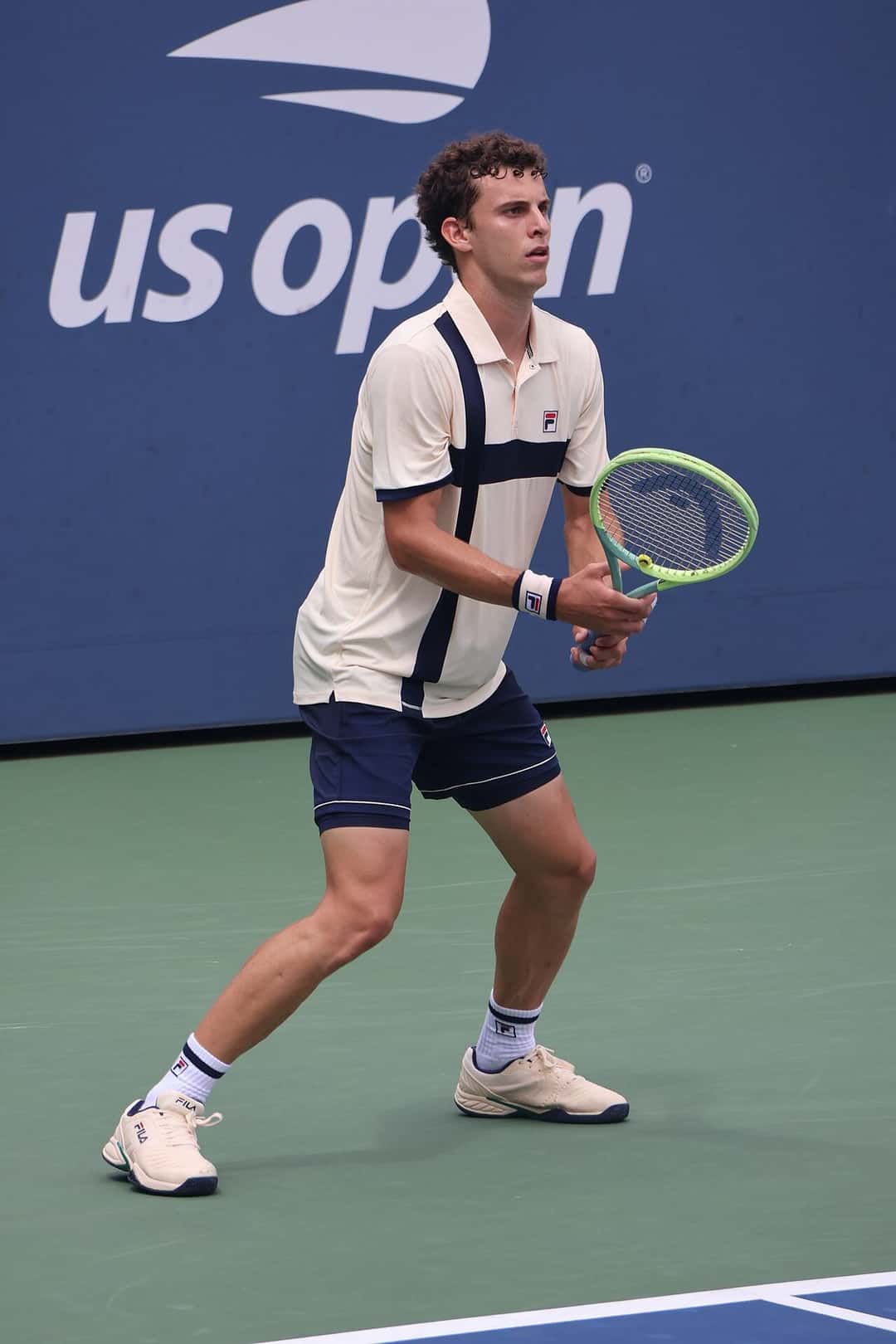 Foto de archivo: Juan Manuel Cerúndolo, con remera blanca y short azul, espera la pelota en posición de devolución en el US Open 2023