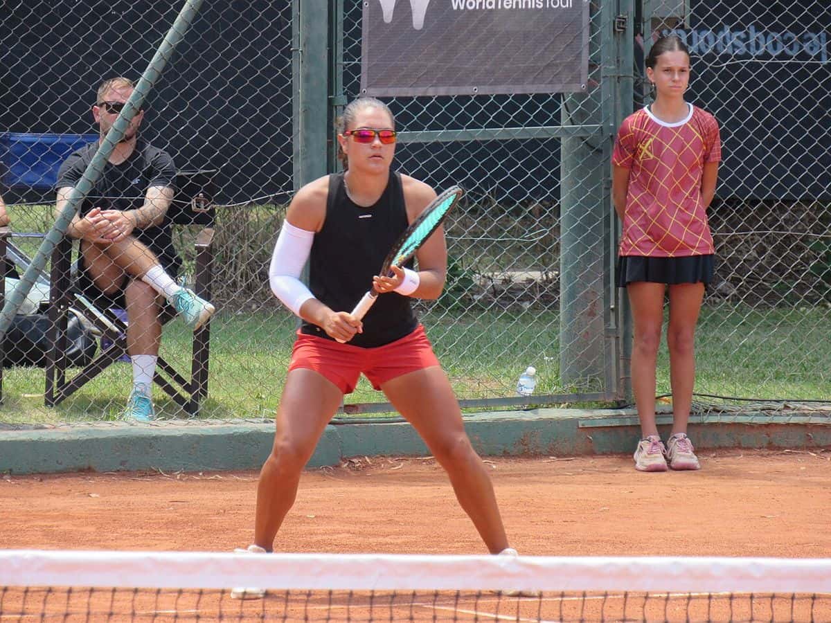Foto de archivo: Luisina Giovannini, con musculosa negra y short rojo, espera el saque en posición de devolución en una cancha de polvo de ladrillo